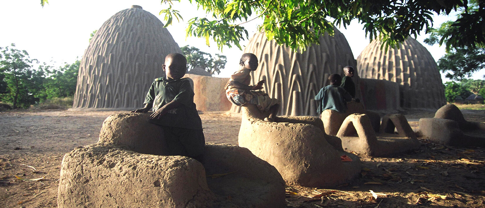 Enfants dans un village jouant autour des cases au cours d'un voyage au Cameroun avec Nirvatravel